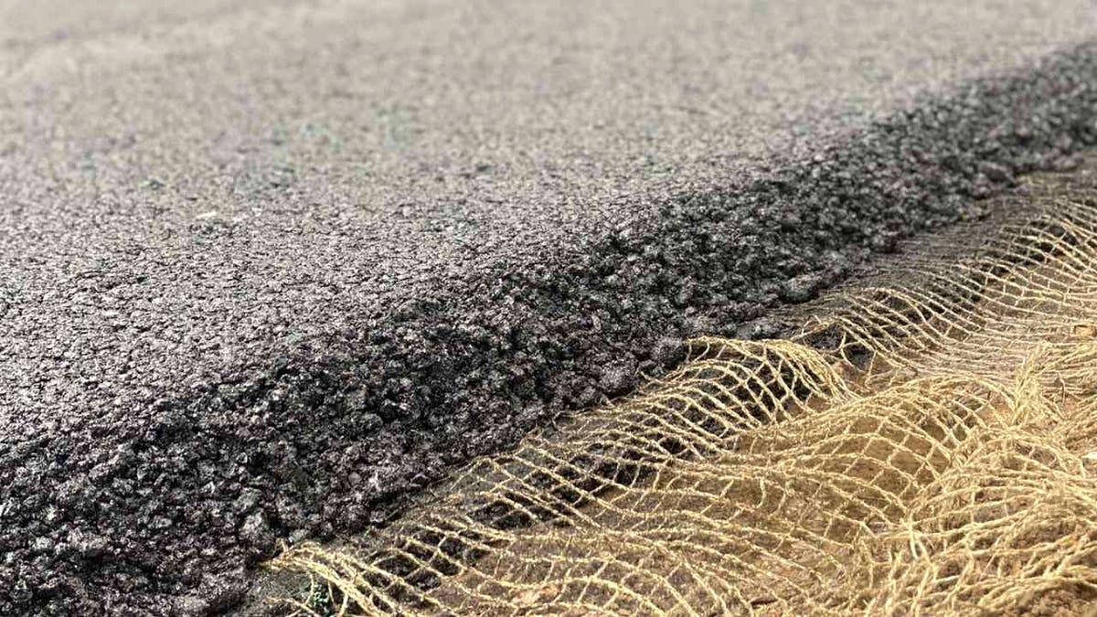 Close-up of new asphalt layer over smart flax-fiber fabric used to detect stress and cracks in roads.