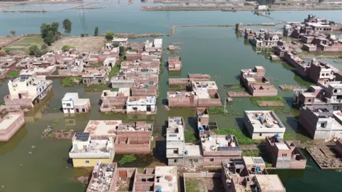 BBC A wide shot of houses sitting in flood waters